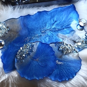 May include: A set of three blue resin coasters with a white and silver swirl design and clear crystal accents.