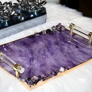 May include: A rectangular serving tray with a purple resin base and gold trim. The tray has two clear acrylic handles and is decorated with small amethyst crystals around the edges.