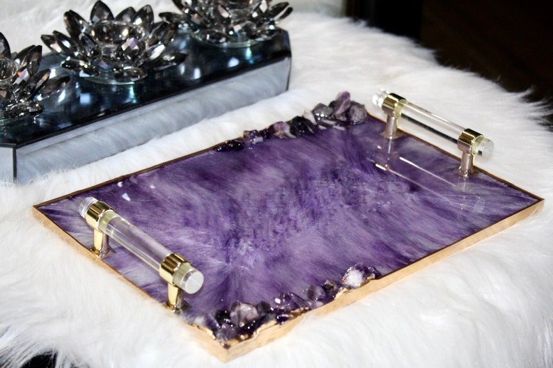 May include: A rectangular serving tray with a purple resin base and gold trim. The tray has two clear acrylic handles and is decorated with small amethyst crystals around the edges.