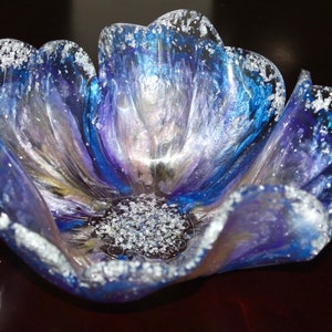 May include: A blue and purple resin flower bowl with silver glitter accents. The bowl is shaped like a flower with multiple petals.