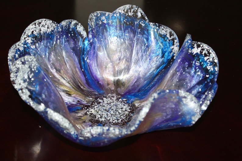 May include: A blue and purple resin flower bowl with silver glitter accents. The bowl is shaped like a flower with multiple petals.