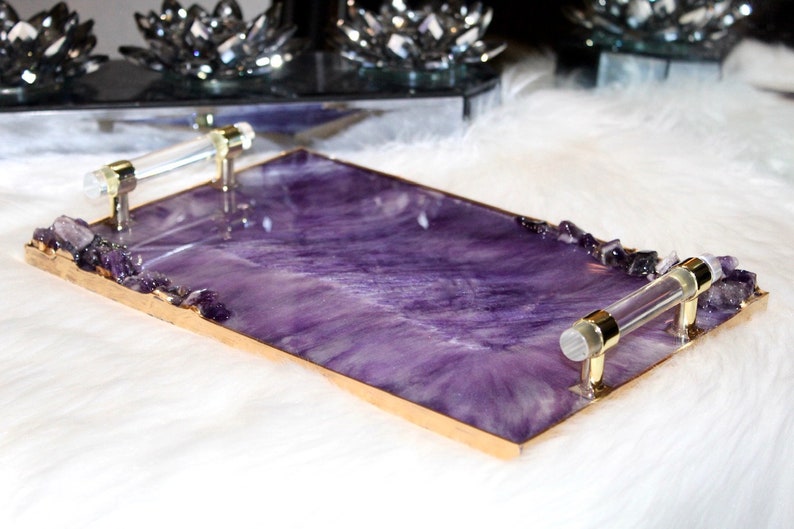 May include: A rectangular serving tray with a purple and white marbled design and gold trim. The tray has two clear acrylic handles with gold accents and is decorated with amethyst crystals.