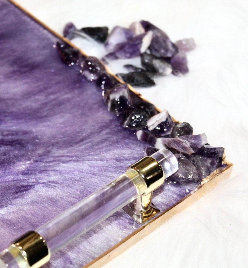 May include: A purple resin tray with a gold rim and a clear acrylic handle. The tray is decorated with amethyst crystals.