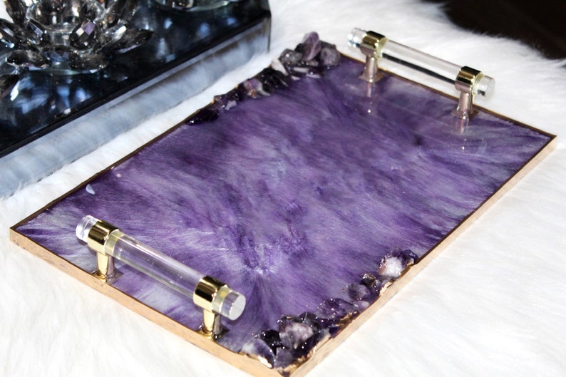 May include: A rectangular serving tray with a purple resin base and gold trim. The tray has two clear acrylic handles and is decorated with amethyst crystals.