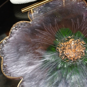 May include: A clear resin tray with a flower design and gold leaf accents. The tray has a gold handle and is perfect for serving snacks or drinks.