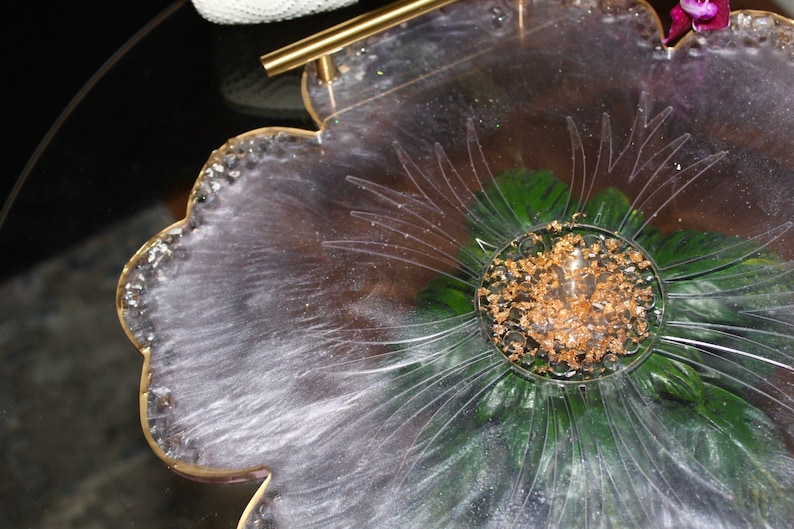 May include: A clear resin tray with a flower design and gold leaf accents. The tray has a gold handle and is perfect for serving snacks or drinks.