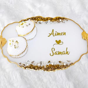 May include: White serving tray with gold accents and a scalloped edge. The tray has two white seashell-shaped dishes and the names "Aimen" and "Samah" written in gold lettering.