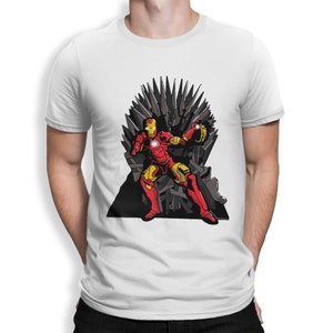 May include: A white t-shirt with a graphic of Iron Man sitting on the Iron Throne from Game of Thrones. The Iron Throne is made of swords and Iron Man is wearing his red and gold armor.