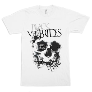 Op de afbeelding: Wit T-shirt met de bandnaam "Black Veil Brides" in grijze en zwarte letters boven een zwart-grijze schedelafbeelding. De schedel heeft gedetailleerde schaduwen en een bloemenontwerp in een oogkas.