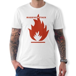 Puede incluir: Camiseta blanca con un gráfico de llama roja y el texto "MASSIVE ATTACK" impreso en la parte delantera.
