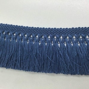 May include: Blue fringe trim with a woven design. The fringe is approximately 1 inch long.