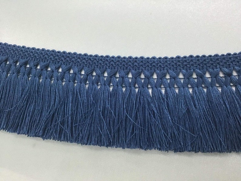 May include: Blue fringe trim with a woven design. The fringe is approximately 1 inch long.