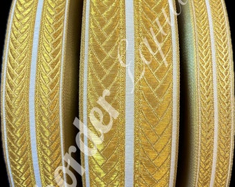 Op de afbeelding: Drie spoelen met gouden en witte bies met een chevron-patroon. De bies is ongeveer 2,5 cm breed.