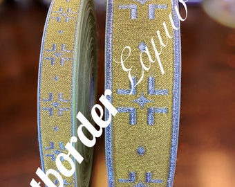 May include: Two rolls of decorative ribbon. The ribbon is gold with a silver geometric pattern and silver trim. The text "Artborder" is written diagonally on the left roll. The text "Eavwins" is written diagonally on the right roll.