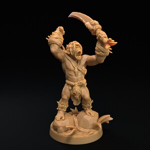 May include: A brown miniature figurine of a humanoid creature with a large, toothy mouth, holding a curved blade in one hand. The creature is wearing a loincloth and has a skull hanging from its waist. The figurine is standing on a base with a rocky texture.