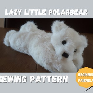 Könnte beinhalten: Ein Nähmuster für einen weißen Plüsch-Eisbären, beschriftet mit "LAZY LITTLE POLARBEAR" und "BEGINNER FRIENDLY" in gelbem Text.