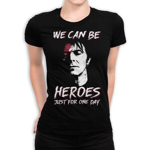 May include: Black t-shirt with a white graphic of a man's face with a red stripe across his eye. The text "WE CAN BE HEROES JUST FOR ONE DAY" is printed below the image.