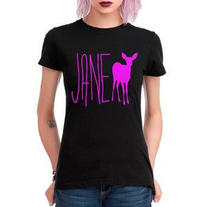 Könnte beinhalten: Schwarzes T-Shirt mit einem pinkfarbenen Grafikdruck eines Rehs und dem Wort "JANE" in einer stilisierten Schrift.