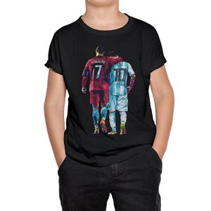 May include: Black t-shirt featuring a colorful illustration of two soccer players, one in a red jersey with the number 7 and the name "Ronaldo," and the other in a light blue jersey with the number 10 and the name "Messi."