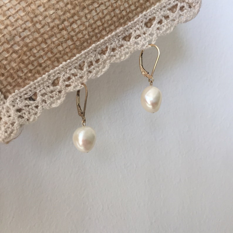 May include: A pair of gold dangle earrings with white pearl drops.