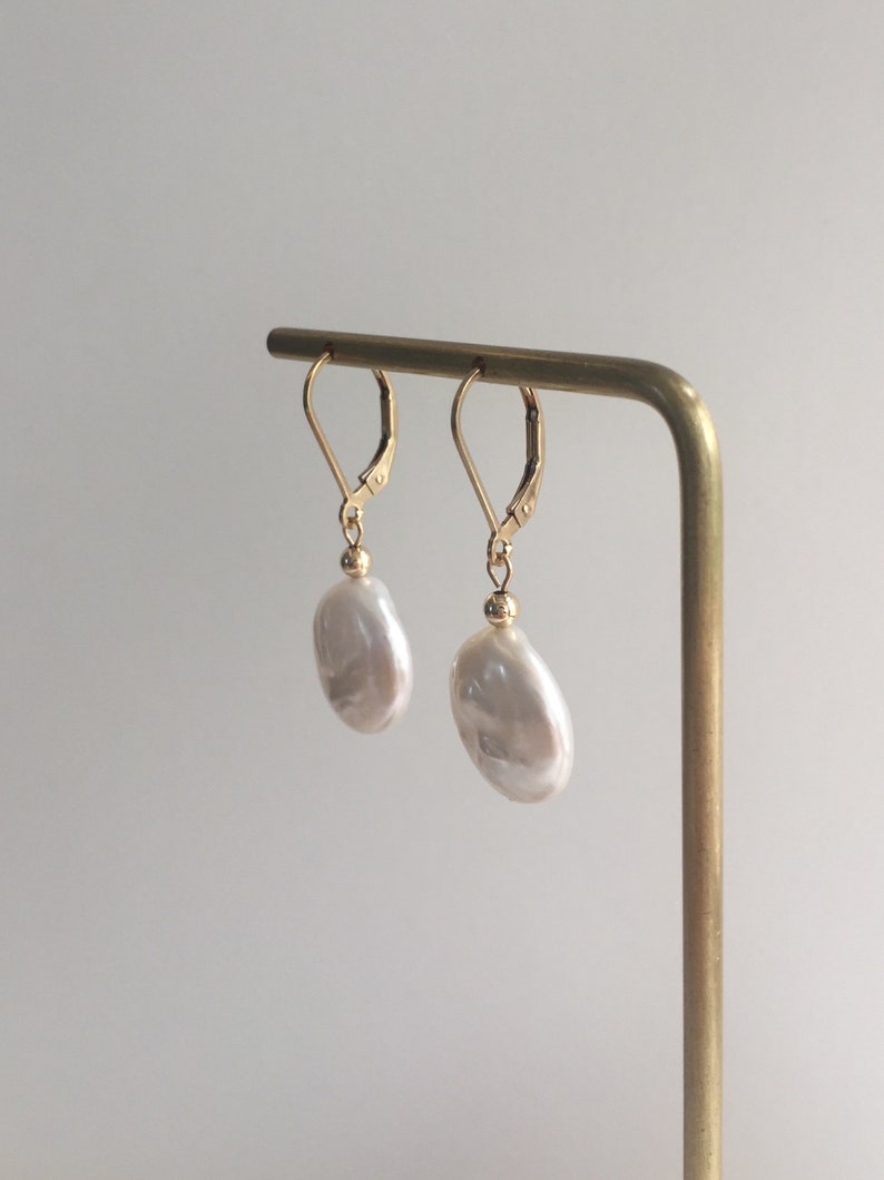 May include: A pair of gold earrings with large, white, irregular shaped pearl drops.