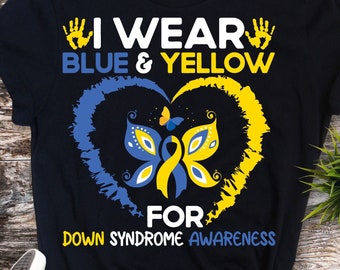 May include: Black t-shirt with the text "I Wear Blue & Yellow For Down Syndrome Awareness." The design features a blue and yellow heart-shaped butterfly. The shirt is paired with black and white sneakers.