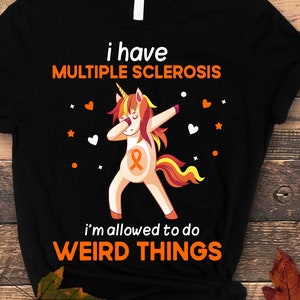 May include: Black t-shirt featuring a white unicorn dabbing and wearing an orange ribbon. The text on the shirt reads "I have Multiple Sclerosis I'm allowed to do weird things."