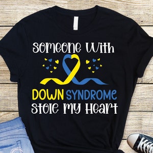 May include: Black t-shirt with a yellow and blue ribbon, hearts, and the text "someone with Down Syndrome stole my heart".