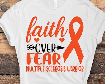 May include: White t-shirt with the words "faith over fear" in orange script, with an arrow and an orange ribbon. The text "Multiple Sclerosis Warrior" is below the main text. The shirt is on a wooden background.