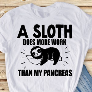 May include: White t-shirt with black text that reads "A sloth does more work than my pancreas". A cartoon sloth is sleeping on a pillow.