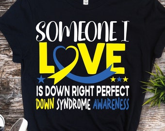 Pode incluir: Camiseta preta com o texto "Someone I Love is Down Right Perfect Down Syndrome Awareness" em branco. Uma fita amarela e azul em forma de coração.