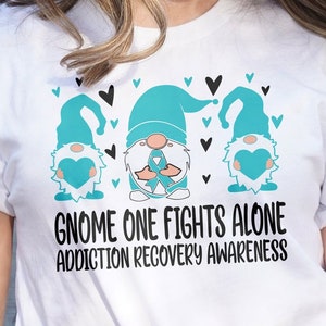 May include: White t-shirt with a teal blue gnome design and the text "Gnome One Fights Alone Addiction Recovery Awareness".