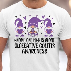 May include: White t-shirt with a purple gnome graphic and the text "Gnome One Fights Alone Ulcerative Colitis Awareness".