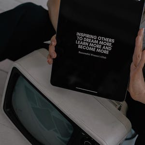 May include: A black tablet with a white background displaying the text "Inspiring others to dream more, learn more and become more. Successful Women's Club".