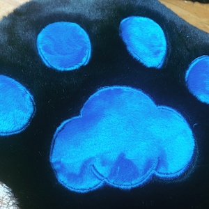 May include: A black furry paw print with blue felt paw pads.