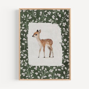May include: A framed watercolor print of a fawn. The fawn is brown with white spots and is set against a white background. The frame has a green floral pattern.