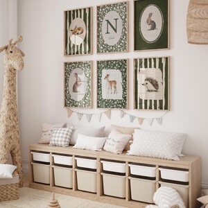 May include: A children's room featuring framed animal art prints, including a fox, rabbit, deer, and hedgehog. The prints are in green and white, with a wooden storage bench below, filled with white bins. Pillows and a giraffe toy complete the decor.