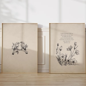 May include: Two framed art prints with botanical illustrations. One features two birds perched on a branch, the other displays a floral arrangement with text from Matthew 6:26. The prints have a neutral color palette and are displayed on a wooden floor.