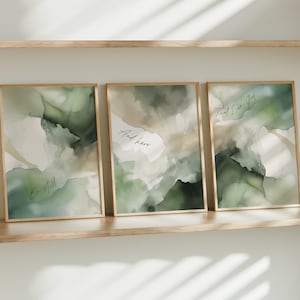 May include: Three framed prints with abstract watercolor-style designs in shades of green and white. The prints have inspirational quotes: "Be still", "And know", and "That I am God".