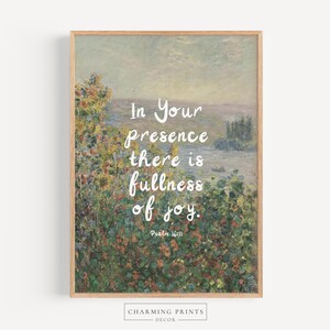 May include: A framed art print featuring a landscape painting with a quote in white script: "In Your presence there is fullness of joy." The artwork has a light brown wooden frame and a floral and landscape background.