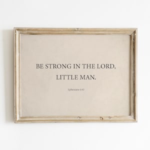 May include: A framed print with a beige background and black text that reads "Be strong in the Lord, little man. Ephesians 6:10".