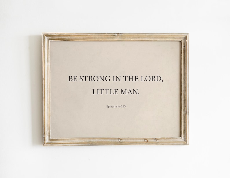 May include: A framed print with a beige background and black text that reads "Be strong in the Lord, little man. Ephesians 6:10".