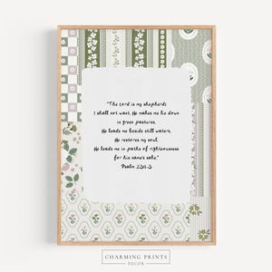 May include: A framed print featuring a patchwork design with floral and geometric patterns in shades of green, white, and beige. The print includes a Bible verse in black script. The frame is a light brown color.