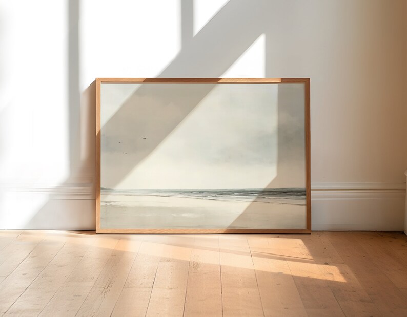 May include: A framed painting of a seascape with a light blue sky, white clouds, and a sandy beach with a calm ocean in the distance.