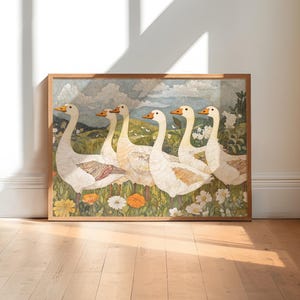 May include: A framed artwork featuring six white geese with orange beaks and feet, set against a backdrop of a green field, flowers, and a cloudy sky. The artwork is in a wooden frame and rests on a wooden floor.