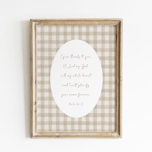 May include: A framed print with a beige and white gingham pattern background. The print features a white oval with a bible verse in cursive script: "I give thanks to you O Lord my God, with my whole heart, and I will glorify your name forever. Psalm 56:12"