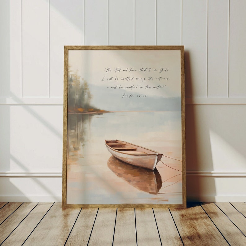 K&ouml;nnte beinhalten: Ein gerahmter Druck mit einem Aquarellbild eines kleinen Bootes auf einem See. Der Himmel ist in einem sanften Blau gehalten und das Wasser ist hellblau mit einem Hauch von Rosa. Das Zitat "Seid still und erkennt, dass ich Gott bin. Ich werde erh&ouml;ht werden unter den Nationen. Ich werde erh&ouml;ht werden auf der Erde!" ist in schwarzer Schrift auf wei&szlig;em Hintergrund gedruckt. Das Zitat wird Psalm 46:10 zugeschrieben.