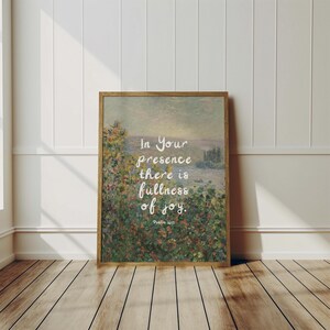 May include: A framed landscape art print with a wooden frame. The artwork depicts a scenic view with text that reads, "In Your presence there is fullness of joy." The print is displayed on a wooden floor.