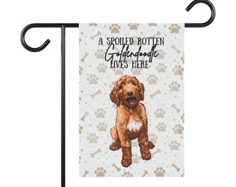 May include: A garden flag with a brown and white paw print pattern. The flag features a cartoon illustration of a golden doodle dog with the text "A Spoiled Rotten Golden Doodle Lives Here".