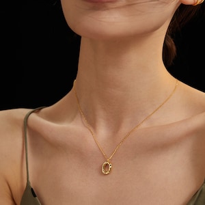 May include: A gold chain necklace with a textured oval pendant.